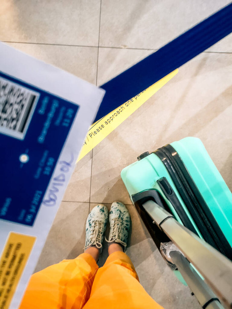 スーツケースと搭乗券を持つ飛行機に乗る前に女性負のcovid-19マークを持つ搭乗券 - 写真・画像