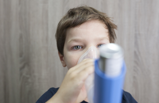 Child boy using medical spray for breath. Inhaler, spacer and mask. Front view - Photo, Image
