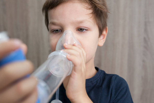 Child boy using medical spray for breath. Inhaler, spacer and mask. Side view - Foto, Bild