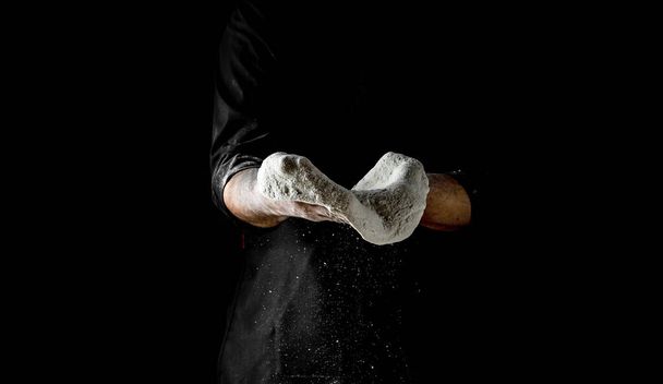 Taputtaa kädet leipuri jauhoja. Kaunis ja vahva miesten kädet vaivaavat taikina tehdä leipää, pastaa tai pizzaa. Ilmaan lentävät jauhemaiset jauhot. - Valokuva, kuva
