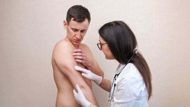 Жінка-лікар в рукавичках оглядає роздратовані груди пацієнта
 - Фото, зображення