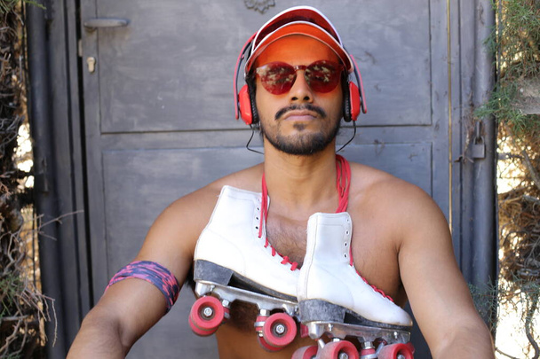 close-up portrait of handsome young mixed race shirtless man with vintage red plastic cap, sunglasses and roller skates - Foto, imagen