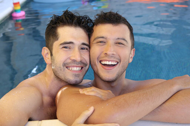 happy young gay couple enjoying their time together in pool - Photo, Image