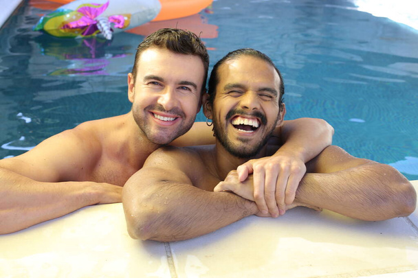feliz joven gay pareja disfrutando su tiempo juntos en piscina - Foto, imagen
