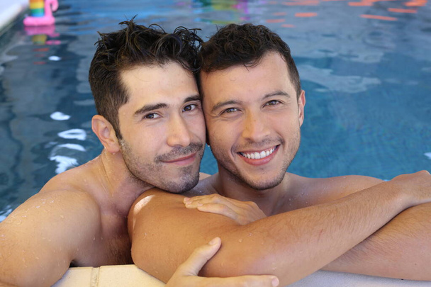 幸せな若いゲイのカップル一緒にプールで彼らの時間を楽しんで - 写真・画像