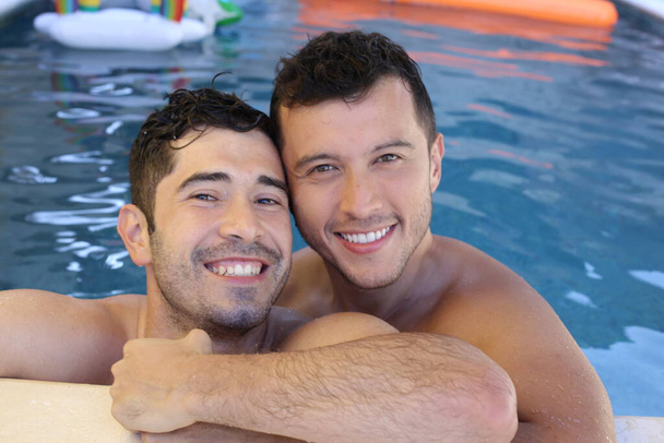 heureux jeune gay couple appréciant leur temps ensemble dans la piscine - Photo, image