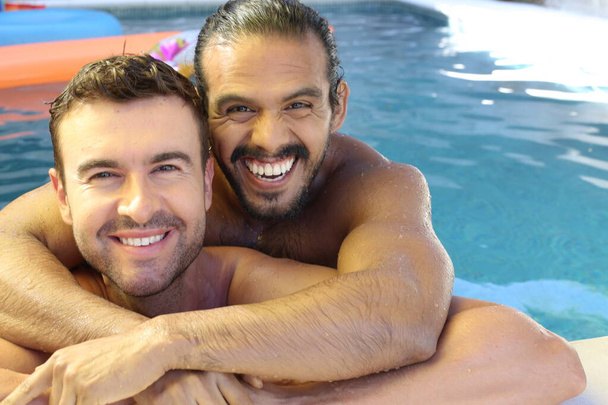 Ευτυχισμένο νεαρό γκέι ζευγάρι που απολαμβάνει το χρόνο του μαζί στην πισίνα - Φωτογραφία, εικόνα