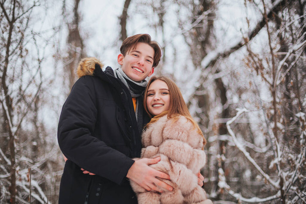 Foto de una hermosa pareja de adolescentes jóvenes que pasan tiempo juntos al aire libre en invierno frío, chico abrazando a la chica para mantenerla caliente en el día helado. Cita romántica al aire libre - Foto, imagen