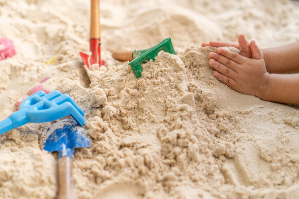 A high angle shot of a child hands playing with toys in a sand box - Foto, Imagen