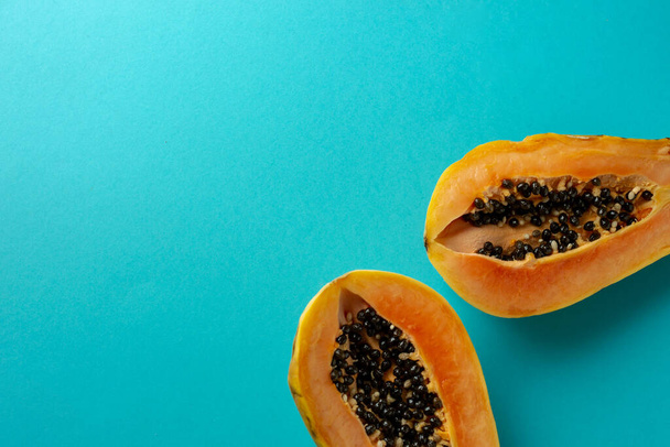 Summer composition. Tropical papaya fruits cut in half lie on a blue background. Summer concept. Flat lay, top view, copy space. - Фото, зображення