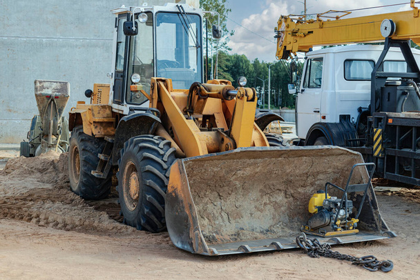 Heavy wheel loader with a bucket at a construction site. Equipment for earthworks, transportation and loading of bulk materials - earth, sand, crushed stone - Photo, Image