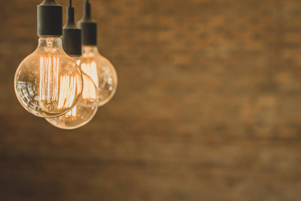 A vintage-style glowing round tungsten lamps hanging on the ceiling - 写真・画像