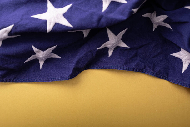 The creased fabric of the American flag isolated on a yellow background - Foto, Imagem