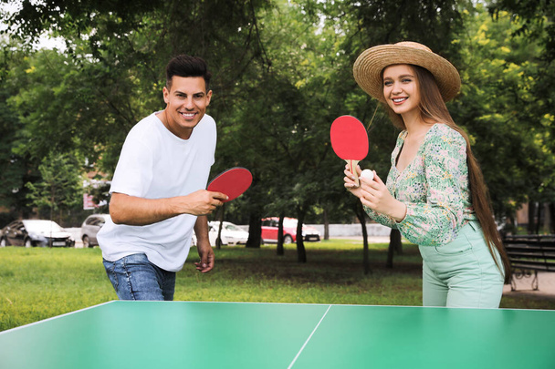 Happy couple playing ping pong in park - Фото, зображення