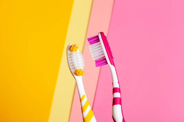 brosses à dents en deux couleurs, jaune et rose. Fond 2 couleurs. Espace de copie. - Photo, image