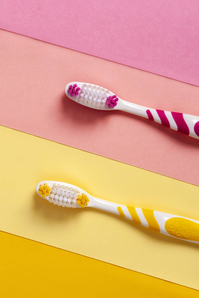 escovas de dentes em duas cores, amarelo e rosa. 2 fundo de cor. Espaço de cópia. - Foto, Imagem