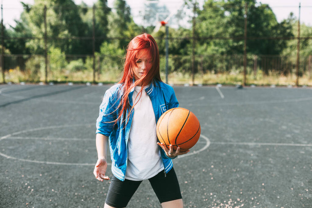 Un joven jugador de baloncesto está entrenando en una cancha de baloncesto al aire libre, una adolescente está jugando baloncesto. Baloncesto, deportes - Foto, imagen