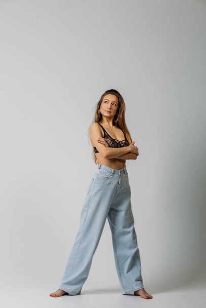 a young beautiful girl, with good body shapes, in a firebox and in jeans, in the studio on a white background, with emotions on her face - 写真・画像