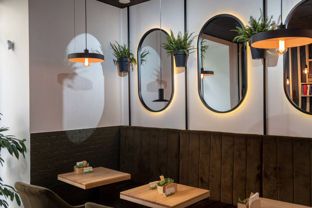 interieur van een gezellig café. Ovale spiegels aan de muur, kleine vierkante tafels. Gezellige sfeer van een coffeeshop - Foto, afbeelding