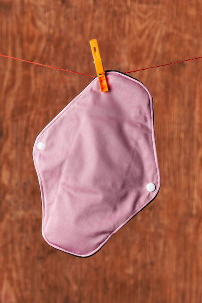 primo piano di un panno rosa pad mestruale appeso su una linea di vestiti con una molletta - Foto, immagini