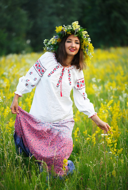 彼の hea に花輪を捧げるとウクライナの衣装で若い女の子に笑みを浮かべて - 写真・画像