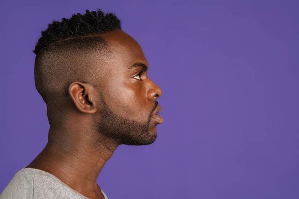 Side view. African-american young mans portrait on purple color studio background. Concept of human emotions, facial expression, youth, feelings, ad. - Fotografie, Obrázek