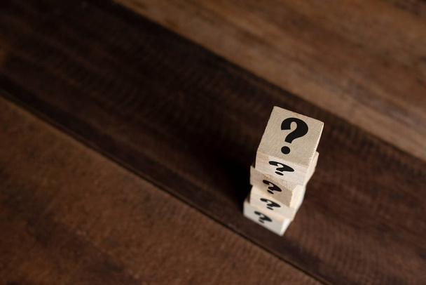 Stacked wooden cube with question mark on table. Concept of FAQ, questions, uncertainty and riddle - Фото, изображение