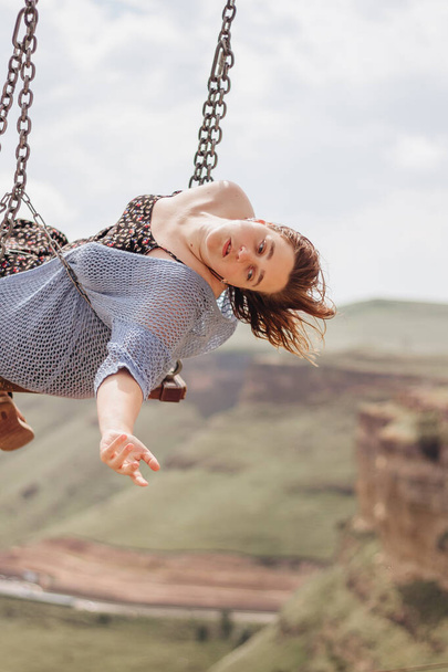 Girl rides on a swing over a cliff in the mountains - Foto, Bild