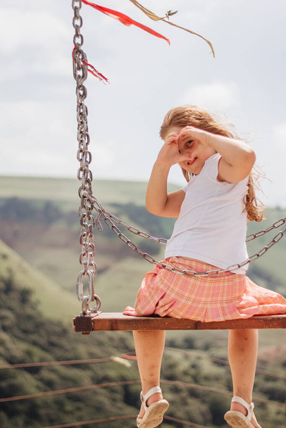 Girl rides on a swing over a cliff in the mountains - Photo, Image