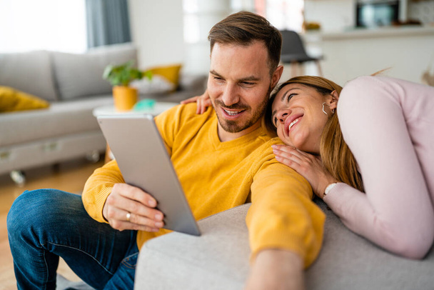 Couple in love hugging and using tablet together at home - Fotoğraf, Görsel