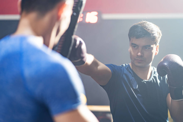 Kaukázusi Fitness oktató tanítani és motiválni fiatal sportoló bokszoló gyakorlat csinál boksz vagy Muay Thai. Atlétikai harcos boksz kesztyű gyakorló ütés és rúgás edző tanár fitness vagy tornaterem - Fotó, kép