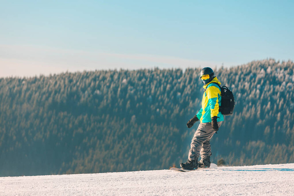 άνθρωπος snowboarding κάτω από λόφο βουνά στο φόντο ηλιόλουστη μέρα - Φωτογραφία, εικόνα