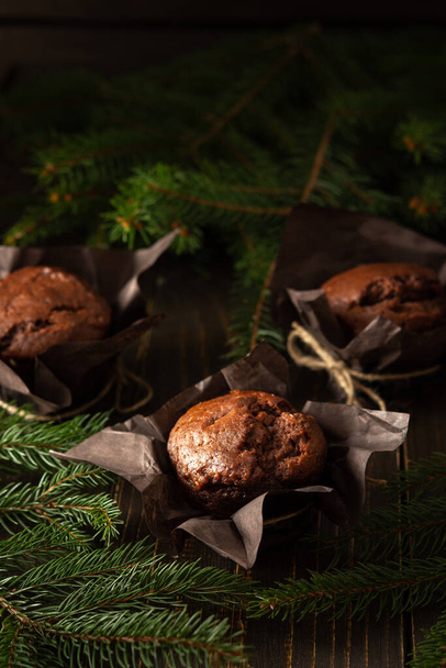 Delicious chocolate muffins on dark wooden background among fir branches, Merry Christmas and Happy New Year - Foto, afbeelding