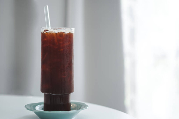 Café noir glacé ou americano en grands verres avec pailles et dessous de verre sur une table de fenêtre dans un café minimaliste. Espace de copie. - Photo, image