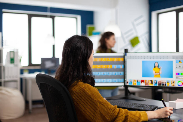 Photographe femme assise au bureau écoutant de la musique à l'aide d'un PC dans un studio photo - Photo, image
