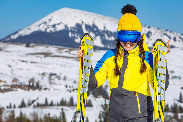 young smiling pretty woman holding ski. mountains on background. winter travel. copy space - Photo, Image