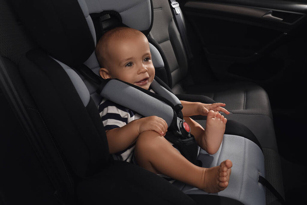 Cute little boy sitting in child safety seat inside car - Fotografie, Obrázek