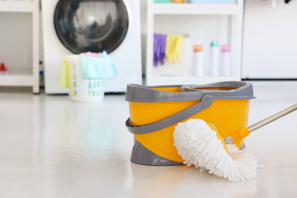 Mop en emmer voor het schoonmaken en dweilen van de vloer in wasruimte thuis, schoonmaken huishoudelijk concept. - Foto, afbeelding