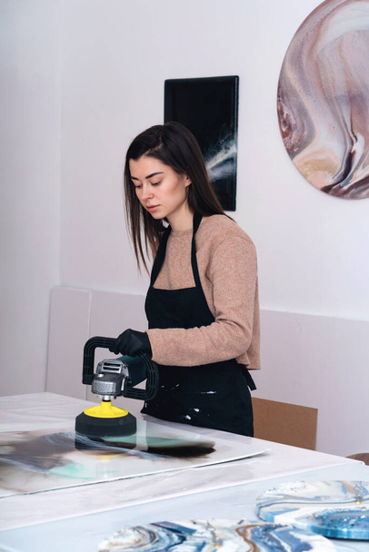 Una máquina de pulir en manos de una joven artista. - Foto, Imagen