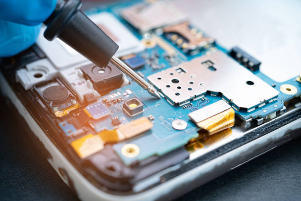 鉄をはんだ付けして携帯電話の内部を修理する技術者。集積回路。データ、ハードウェア、テクノロジーの概念は. - 写真・画像
