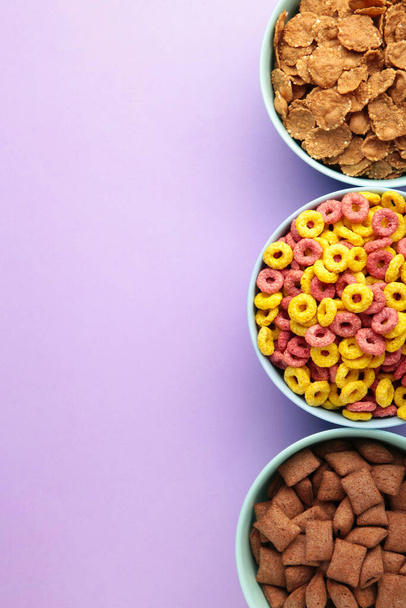 Variety of cereals in blue bowls, quick breakfast on purple background. Top view - Foto, immagini