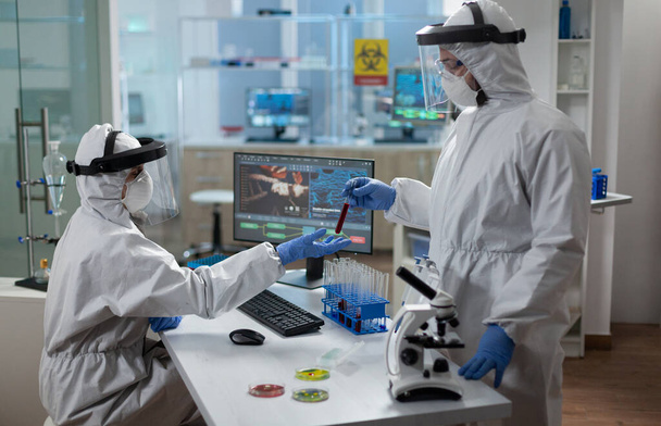 Scienziati che indossano tuta medica contro il merluzzo bianco19 esaminando il sangue infetto - Foto, immagini