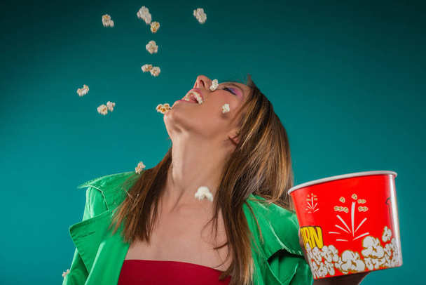 Krásná dívka se baví s popcornem, který vyhazuje do vzduchu - Fotografie, Obrázek