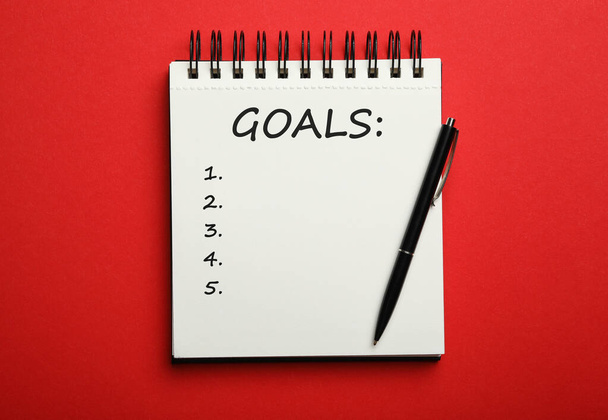 Pen and notebook with inscription GOALS on red background, top view. New Year aims  - Φωτογραφία, εικόνα
