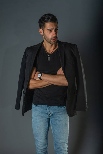 Komea muodikas malli mustassa t-paidassa takki olkapäillään poseeraa studiossa - Valokuva, kuva