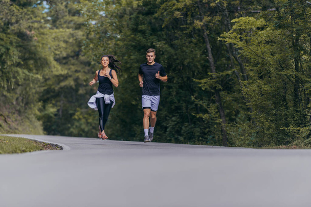 Athletic couple running on a street next to each other. Nature,fit and healthy concept. - Photo, Image