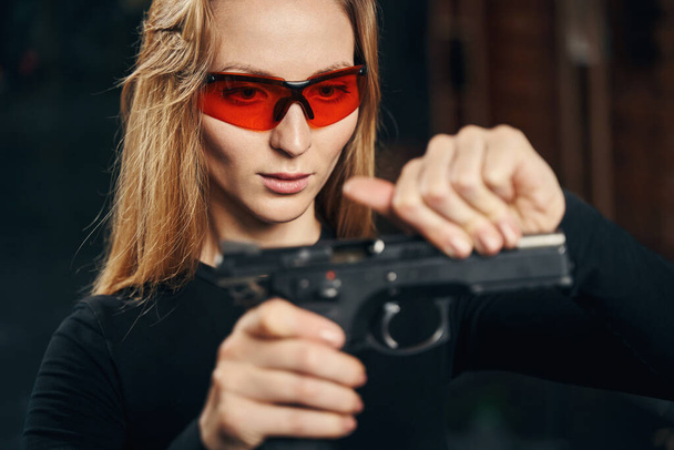 Focused experienced young woman reloading a handgun - Foto, Bild