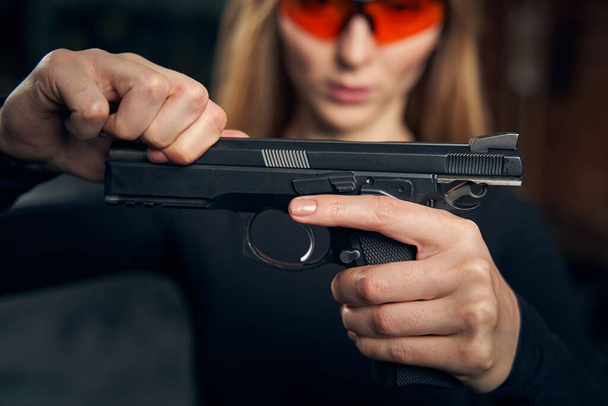 Focused female reloading a pistol before shooting - 写真・画像