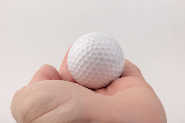 Nahaufnahme Hand hält Golfball auf weißem Hintergrund.  - Foto, Bild