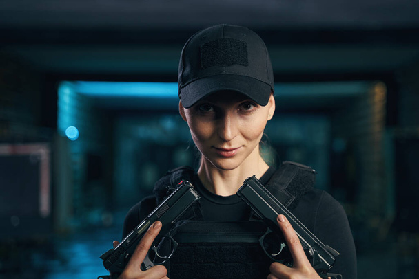 Γαλήνιο γυναικείο shooter ποζάρει για την κάμερα με δύο πιστόλια - Φωτογραφία, εικόνα